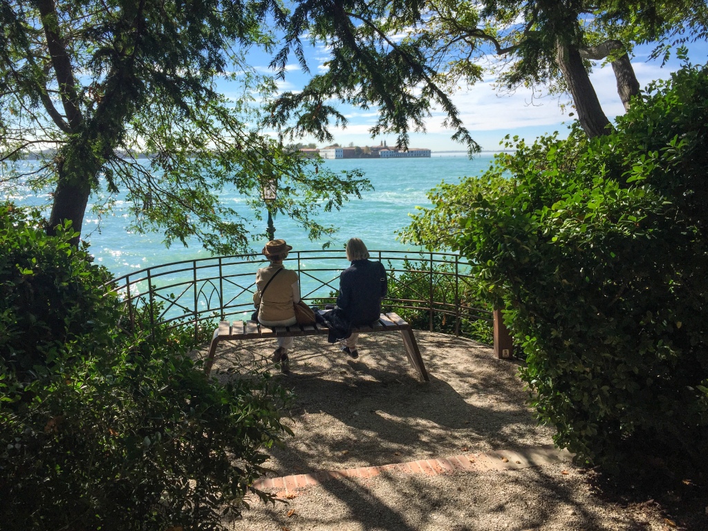 Two ladies sitting on a park bench enjoying the gorgeous view of the Mediterranean Sea in Venice, Italy.